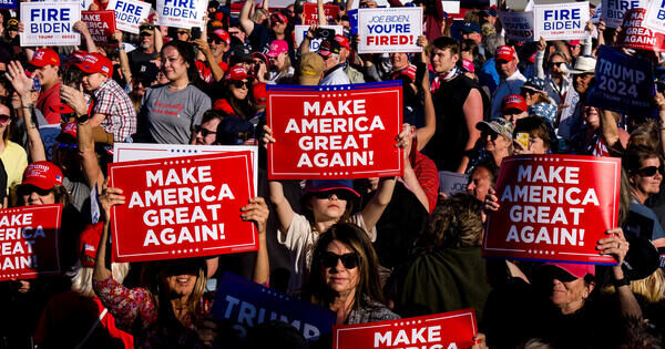 集会人群高举 Make America Great Again 标语牌